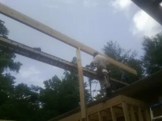 Carpenter setting a ridge beam over a new addition frame — Ice Dam Removal by Roofing Brothers in Keyport