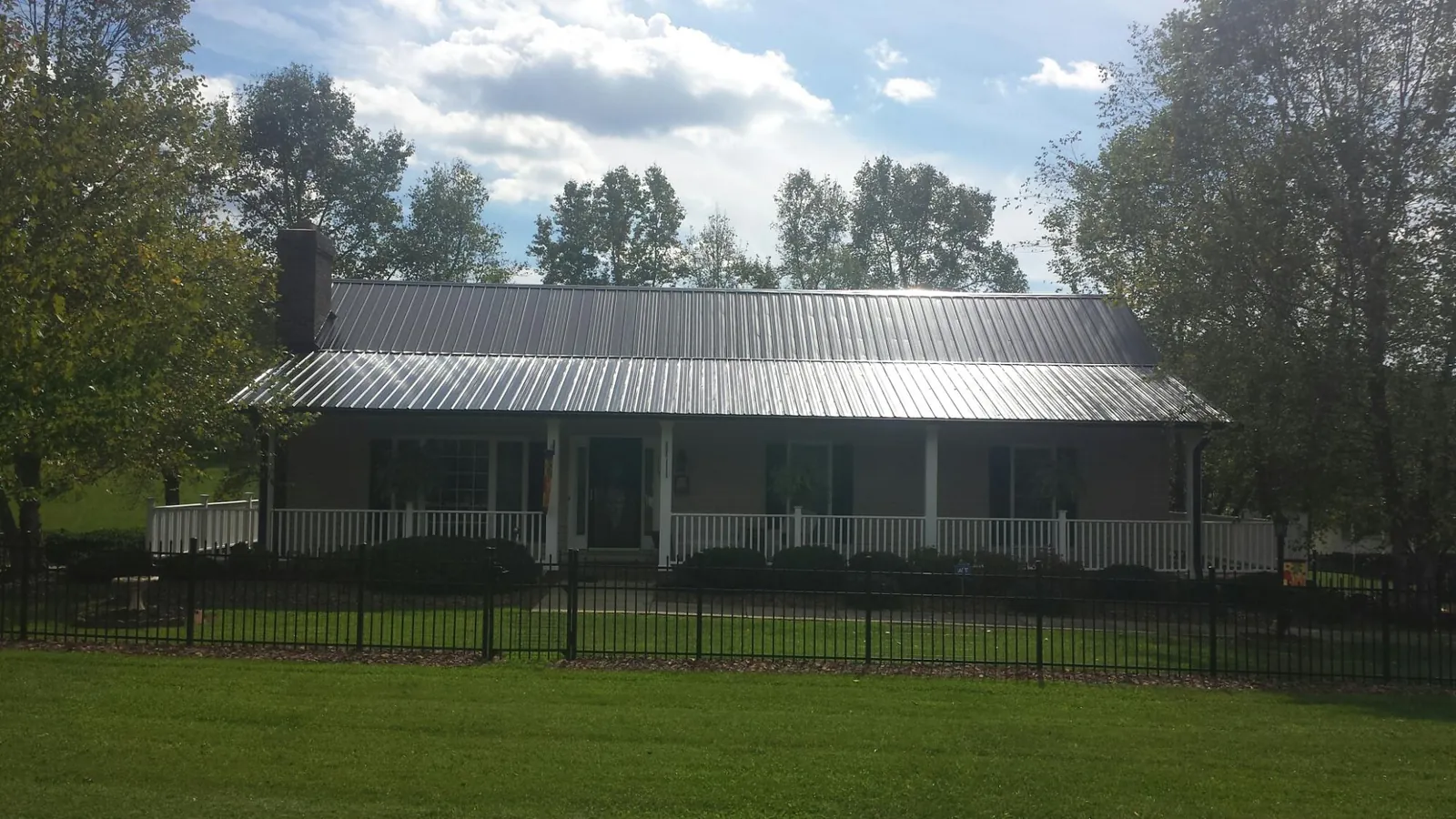 Gray metal roof on a brick ranch with a full width front porch — Gutter Guard Installation work by our crew in Keyport