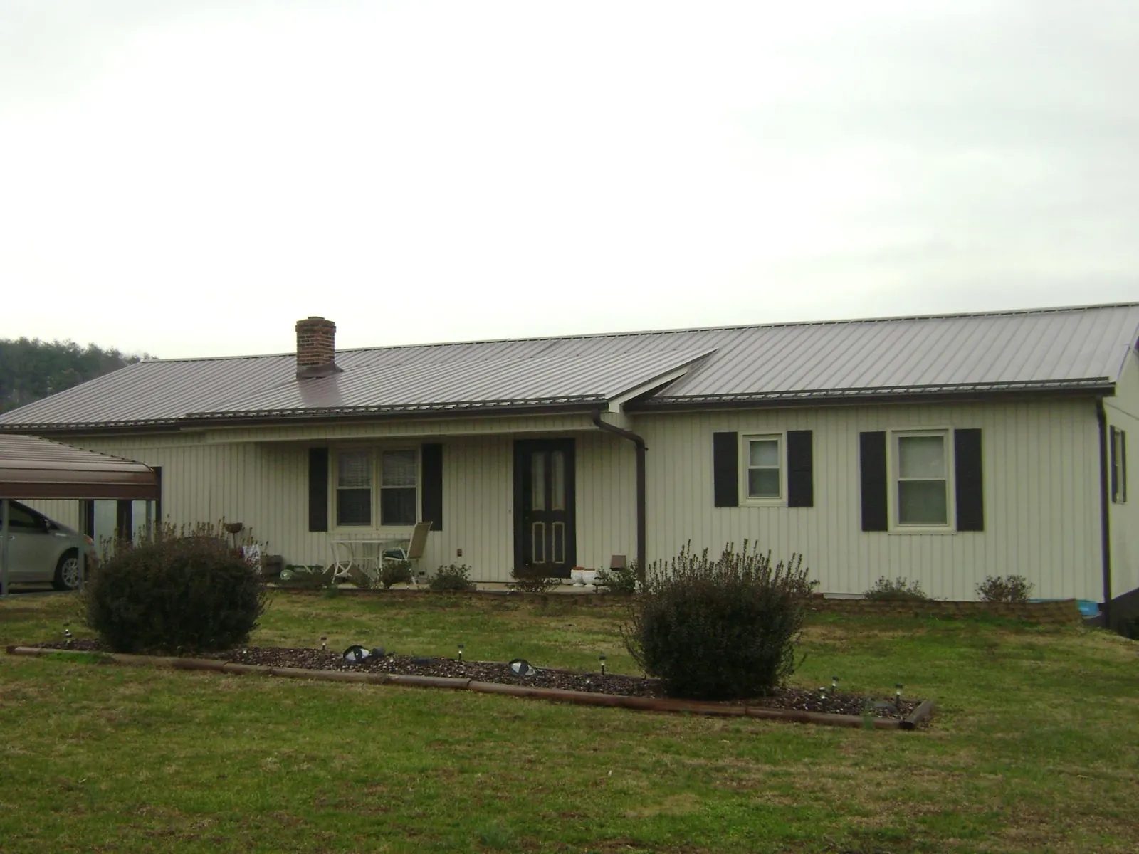 Brown metal roof on a cream sided ranch home with a brick chimney in Keyport