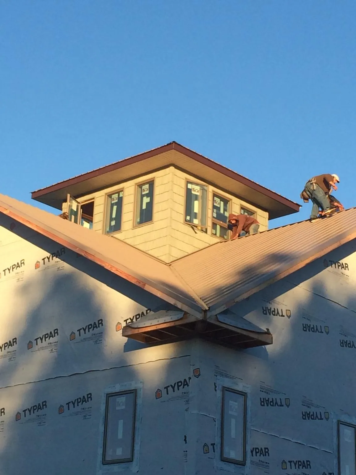 Roofers working around a rooftop cupola on a new metal roof at sunset — Roof Waterproofing in Keyport by Roofing Brothers